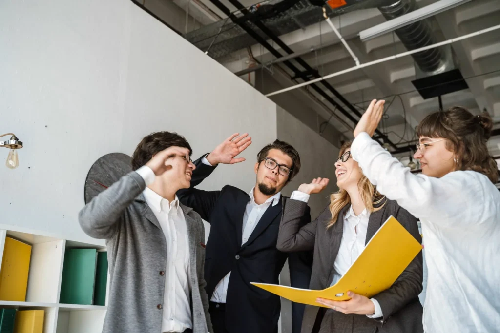 cheerful-young-group-people-standing-office-giving-high-five
